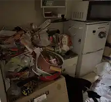 作業前の札幌市中央区の1Kキッチン周辺。冷蔵庫や電子レンジなどの家電に加え、鍋や食器、日用雑貨、段ボールが山積みになり、一人では到底片付けきれないほど荷物が溢れている状態。