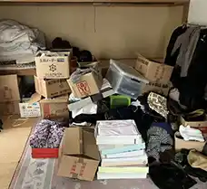 作業前の札幌市北区の一戸建て室内。押し入れや床一面に、衣類、段ボール、贈答品の箱、生活雑貨などが山積みになり、自力での分類・搬出が困難なほど荷物が溢れている状態。エコリングのプロの査定によって、この中から価値ある品が買い取られた。