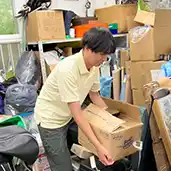 物があふれた部屋で買取可能な商品を探索している様子の写真